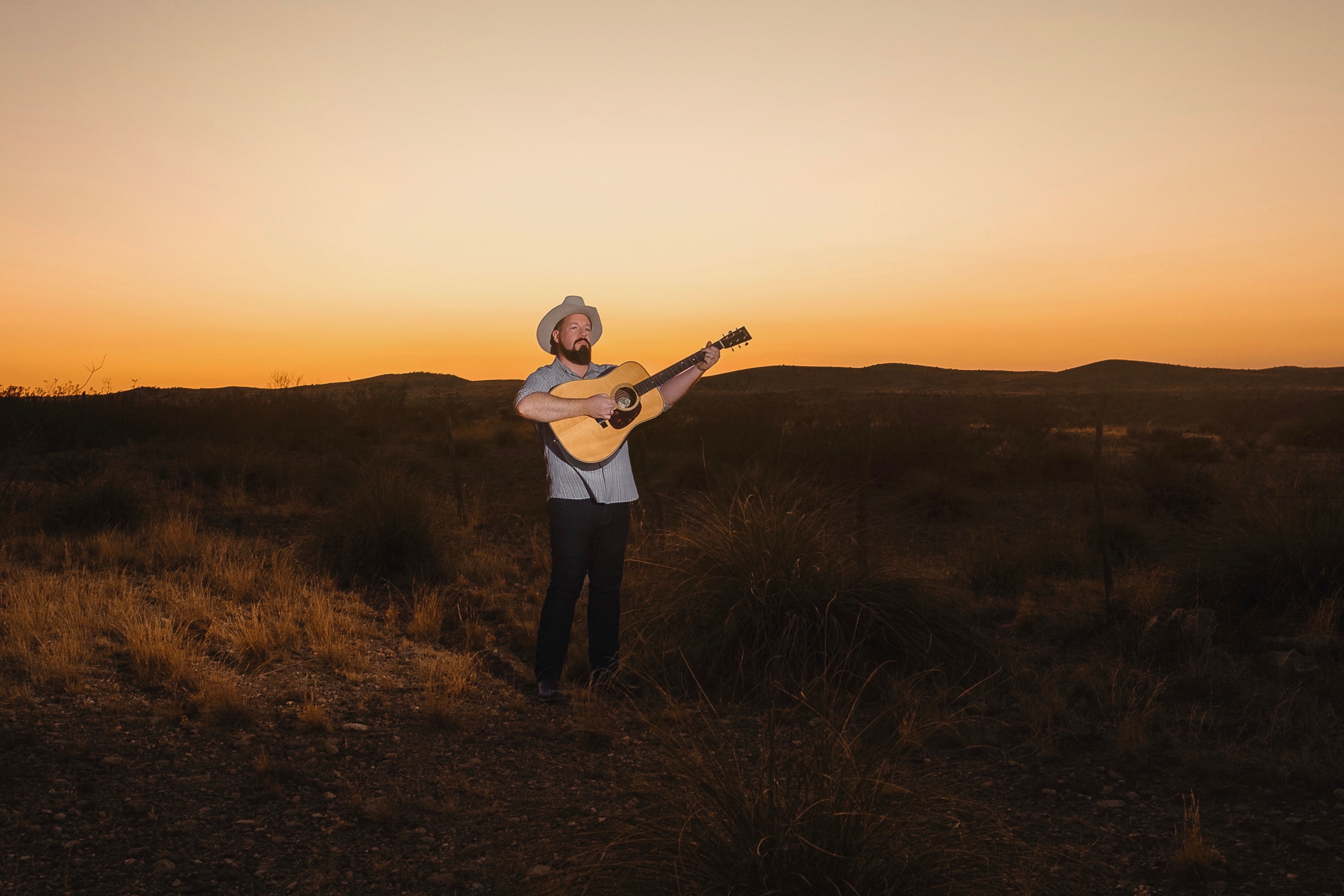 Daniel Miller standing on a desert road at golden hour